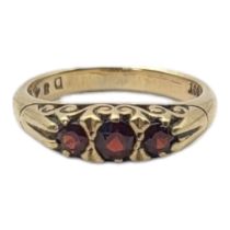 A VINTAGE 9CT GOLD AND GARNET THREE STONE RING Having a row of graduated stones in a scrolled mount.