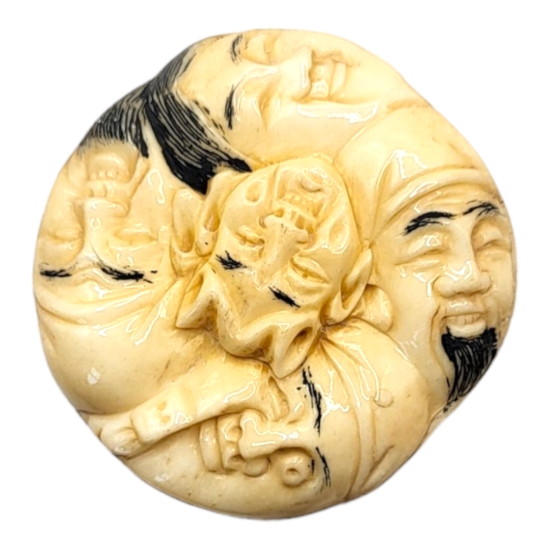 A JAPANESE BONE NETSUKE Circular form, with carved stylised faces to body. (4cm x 1.5cm) - Image 2 of 4