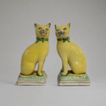 A PAIR OF STAFFORDSHIRE SEMI PORCELAIN MODELS OF CATS, CIRCA 1900 Both in seated position, wearing a