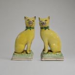 A PAIR OF STAFFORDSHIRE SEMI PORCELAIN MODELS OF CATS, CIRCA 1900 Both in seated position, wearing a