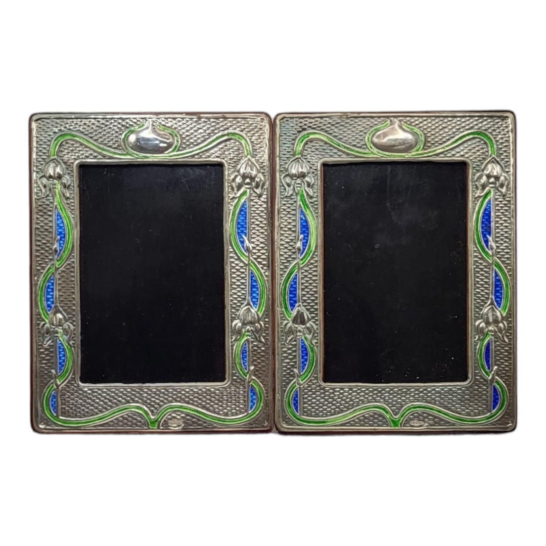 A PAIR OF ART NOUVEAU STYLE SILVER AND ENAMEL PHOTOGRAPH FRAMES Embossed floral design and wooden