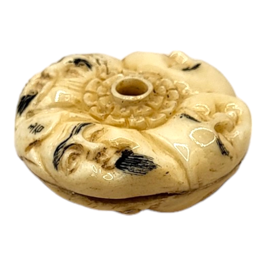 A JAPANESE BONE NETSUKE Circular form, with carved stylised faces to body. (4cm x 1.5cm) - Image 4 of 4