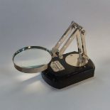 AN EARLY 19TH CENTURY STYLE CHROME ANGLEPOISE MAGNIFYING GLASS On an ebonised wooden plinth. (9cm