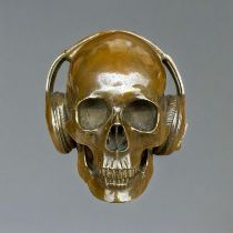 A CONTEMPORARY POLISHED BRONZE SKULL Wearing headphones, sits flush on surface. (19cm x 20cm x 19cm)