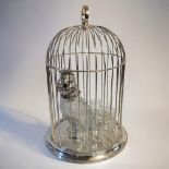 A SILVER PLATE BIRDCAGE DECANTER SET Centrally positioned clear glass and silver plated parrot