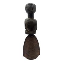 AN AFRICAN CARVED WOODEN FIGURAL HANDBELL Female figure with metal bell to base. (approx 28cm)