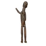 AN AFRICAN LOBI/GHANA CARVED WOODEN FIGURE Elongated female form with one arm raised and shells to