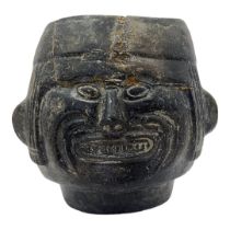 A SOUTH AMERICAN POTTERY FIGURAL VESSEL Having a grimacing face to body and reeds to headdress. (