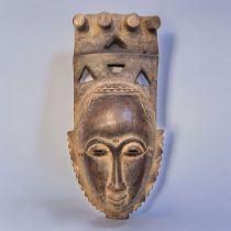 AN AFRICAN TRIBAL CARVED WOODEN BAULE PORTRAIT MASK Having four producing legs to finial and pierced