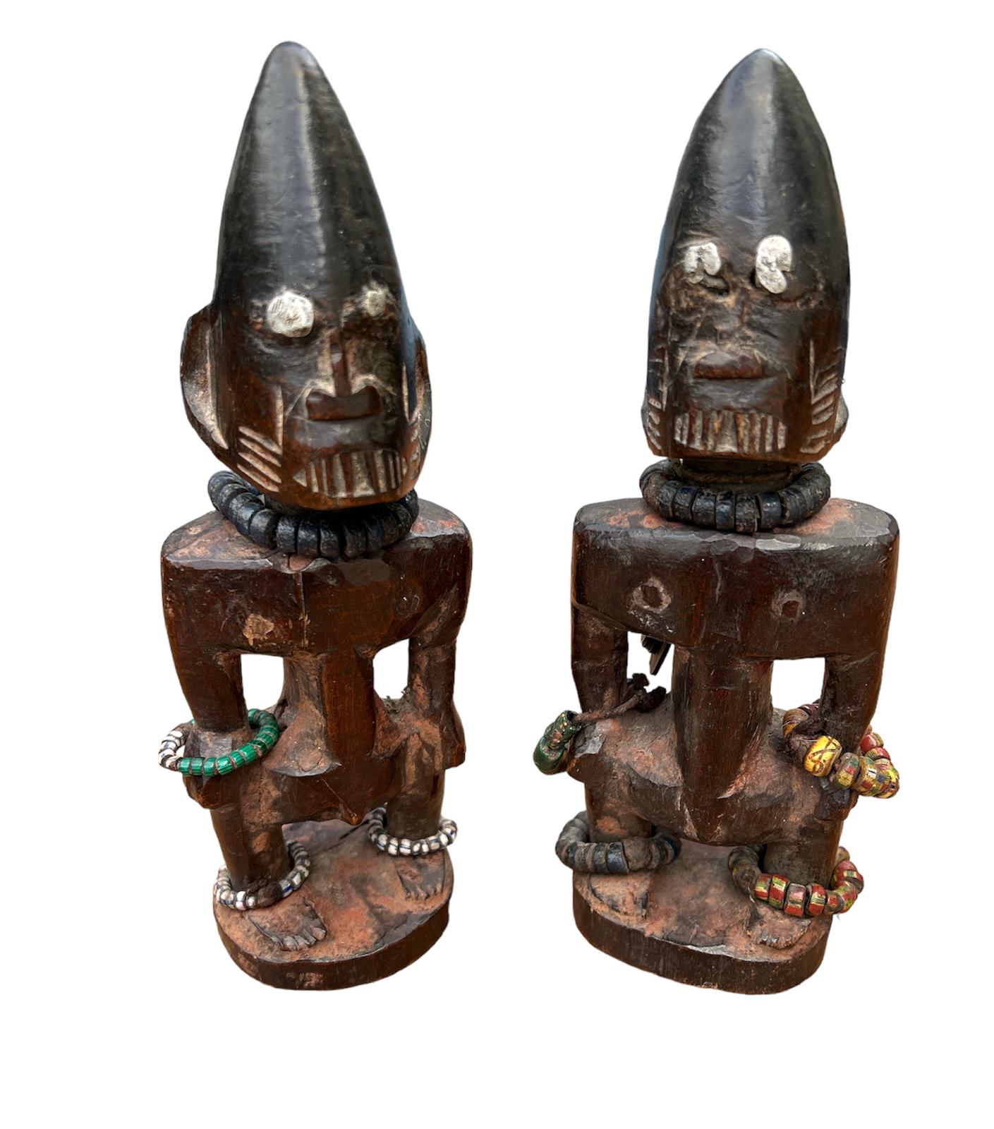 A PAIR OF AFRICAN YORUBA CARVED WOODEN FERTILITY FIGURES Male and female with steel nails to eyes