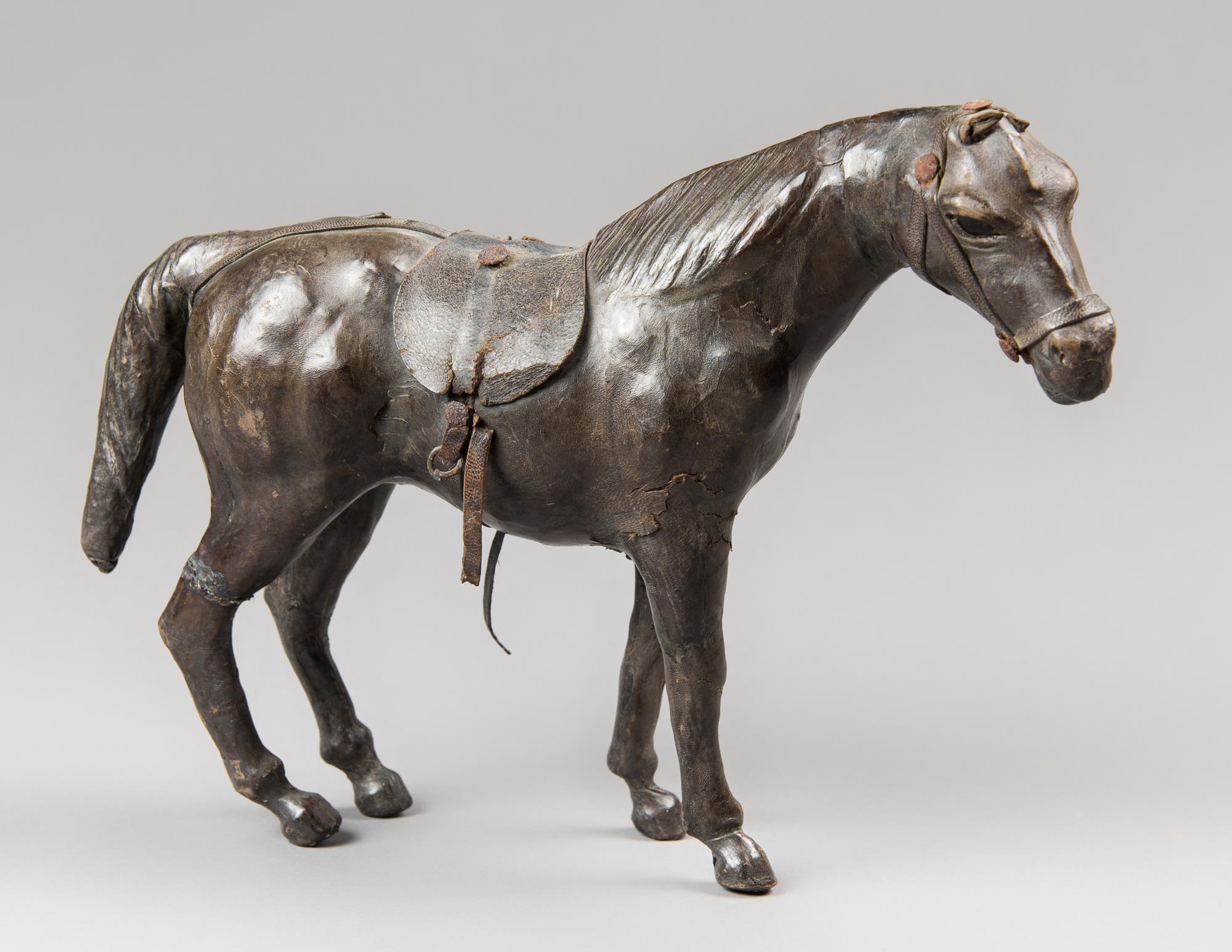 A 19TH CENTURY LEATHER CLAD MODEL OF A HORSE WITH GLASS EYES. (h 23cm x w 31cm x d 10cm)