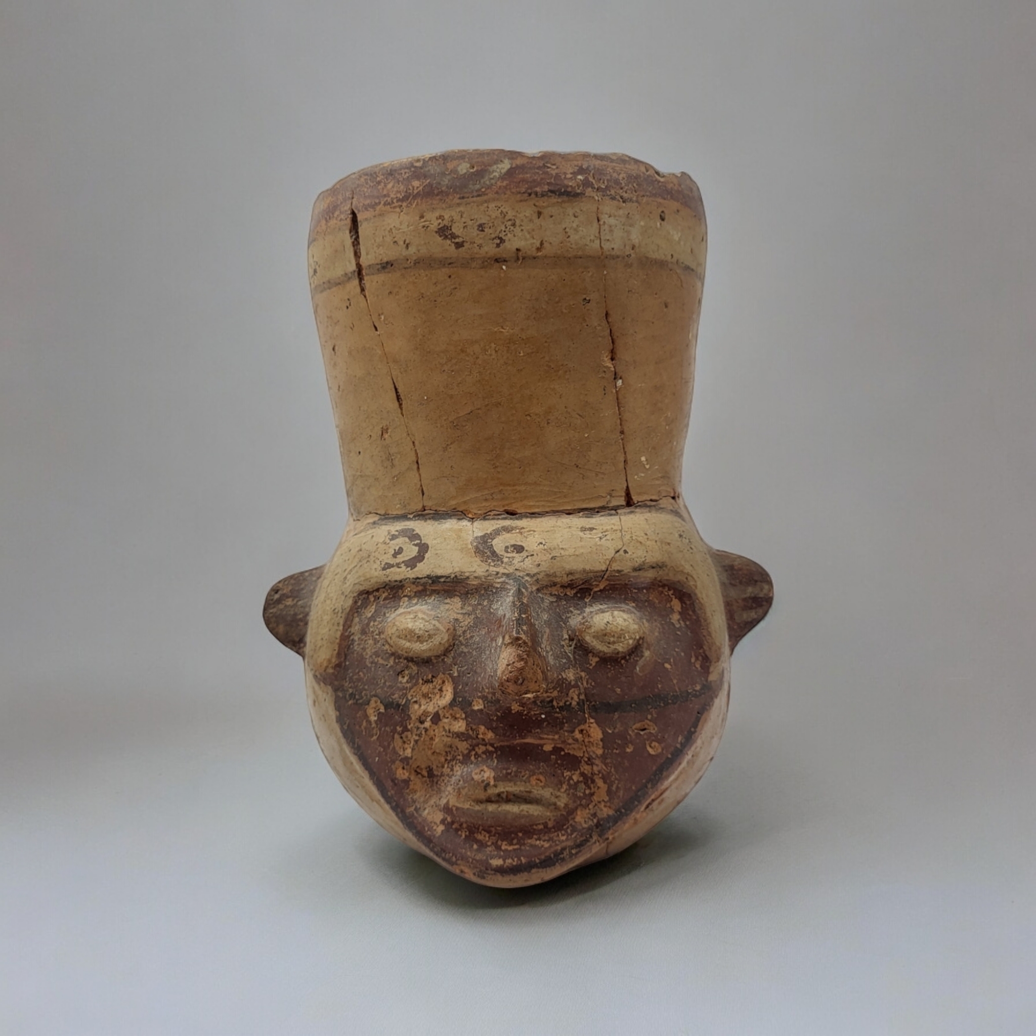 A SOUTH AMERICAN TERRACOTTA POTTERY MASK JUG Carved facial features with painted decoration. (approx