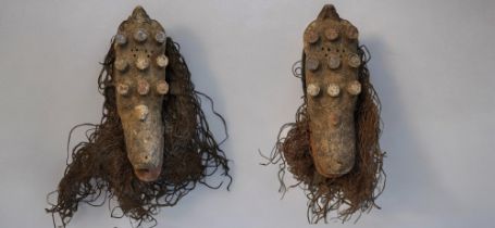 A PAIR OF AFRICAN CARVED WOODEN GREBO MASKS Having nine protruding mounts and old painted