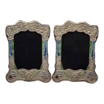 A PAIR OF ART NOUVEAU STYLE SILVER AND ENAMEL PHOTOGRAPH FRAMES Embossed floral design and wooden