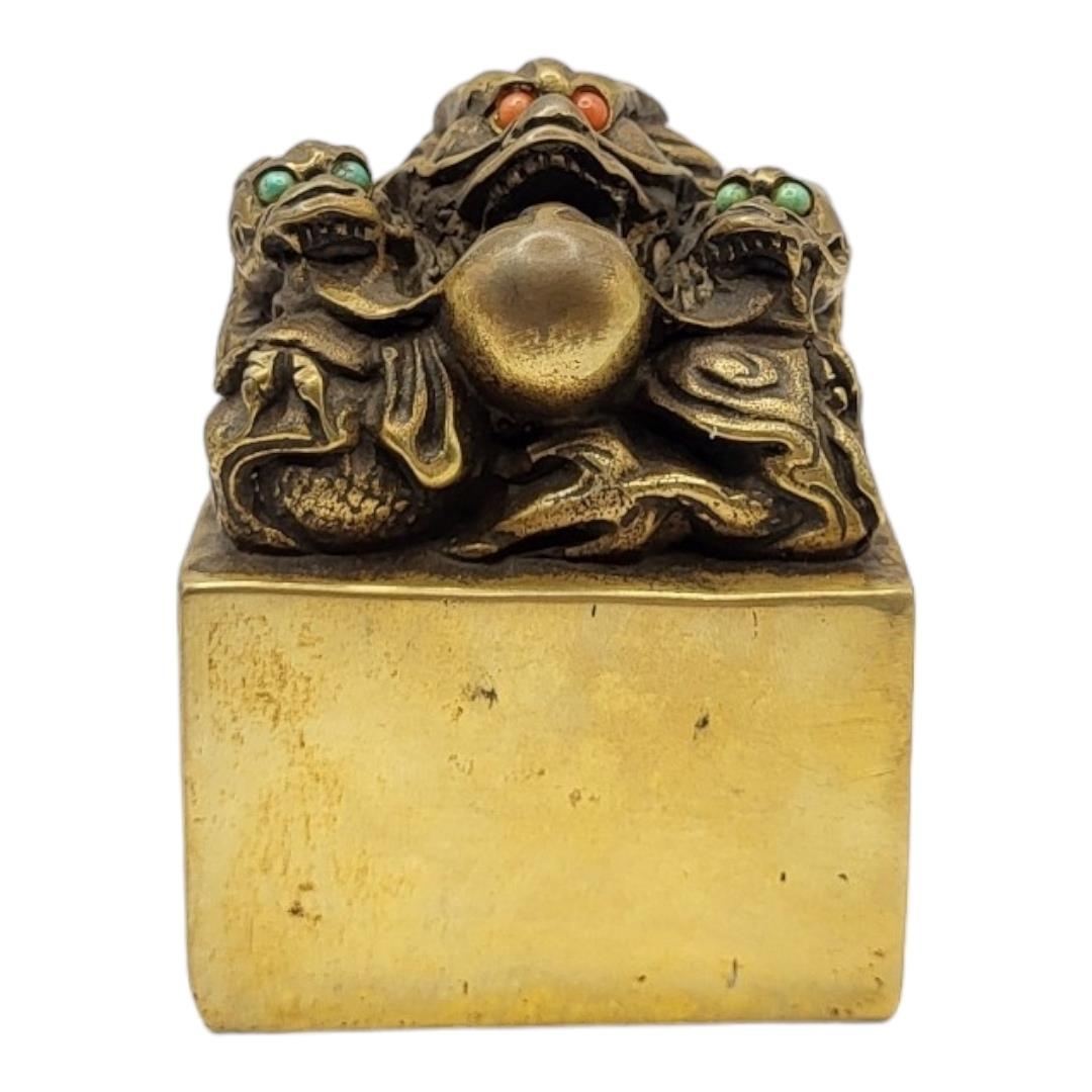 A CHINESE BRONZE DRAGON SEAL The eyes inset with coloured stones on a patinated body, with inscribed