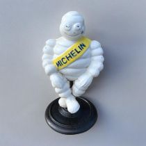 A NOVELTY CAST IRON MICHELIN MAN FIGURE With embossed logo and sash, sat on a rotating support