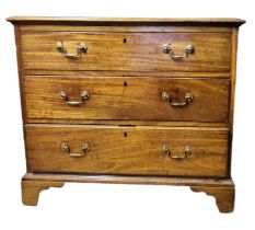 A GEORGIAN SOLID MAHOGANY CHEST OF THREE LONG DRAWERS Fitted with brass swan neck handles, on