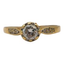 AN 18CT GOLD AND DIAMOND SOLITAIRE RING Having brilliant round cut diamond (approx. 5mm) flanked