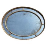 MANNER OF ROBERT ADAM, A GEORGE III OVAL CARVED GILTWOOD SECTIONAL MIRROR With original mercury