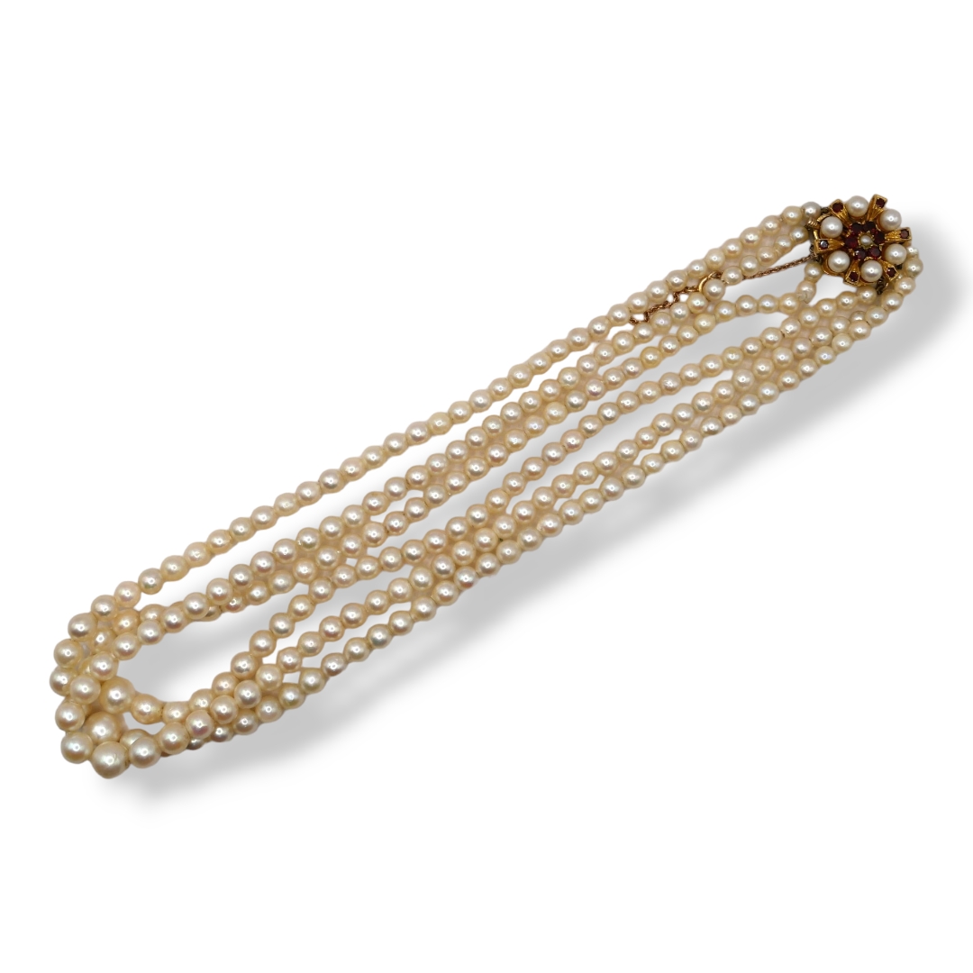 A VINTAGE THREE STRAND PEARL NECKLACE, HAVING DECORATIVE 9CT GOLD, GARNET AND PEARL CLASP Each