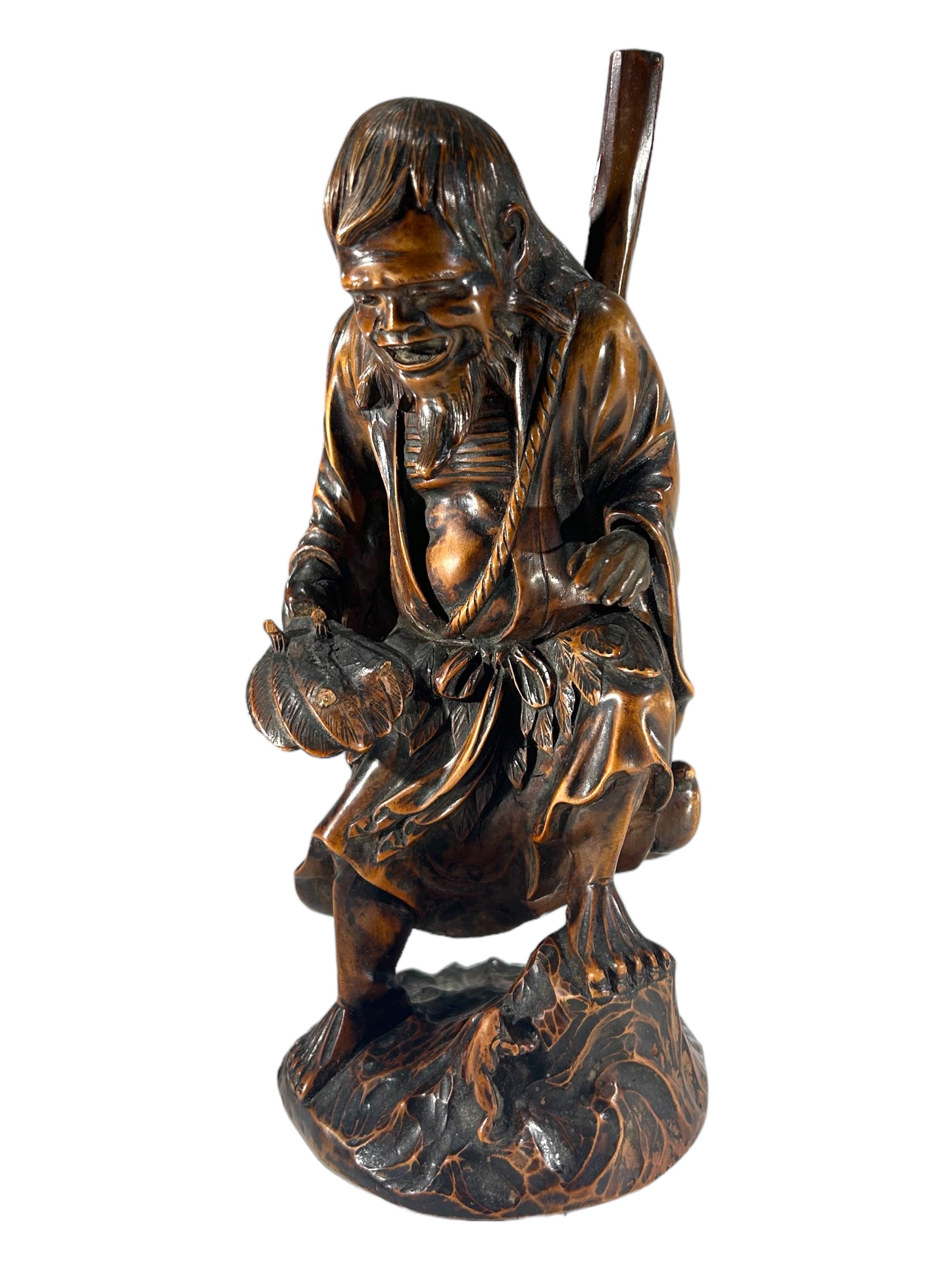 A JAPANESE MEIJI PERIOD CARVED WOODEN FIGURE OF THE DAOIST IMMORTAL, GAMA SENNIN WITH FROG Marked