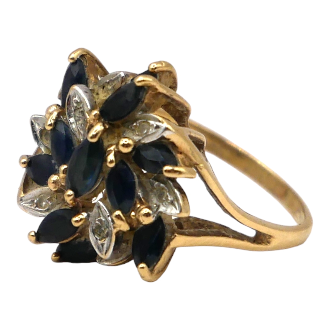 A 9CT GOLD, DIAMOND AND TOPAZ CLUSTER RING Having eleven marquise cut blue topazes (largest