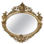 A LARGE AND IMPRESSIVE 19TH CENTURY CARVED GILTWOOD AND GESSO OVAL MIRROR With central female facial