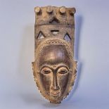 AN AFRICAN TRIBAL CARVED WOODEN BAULE PORTRAIT MASK Having four producing legs to finial and pierced