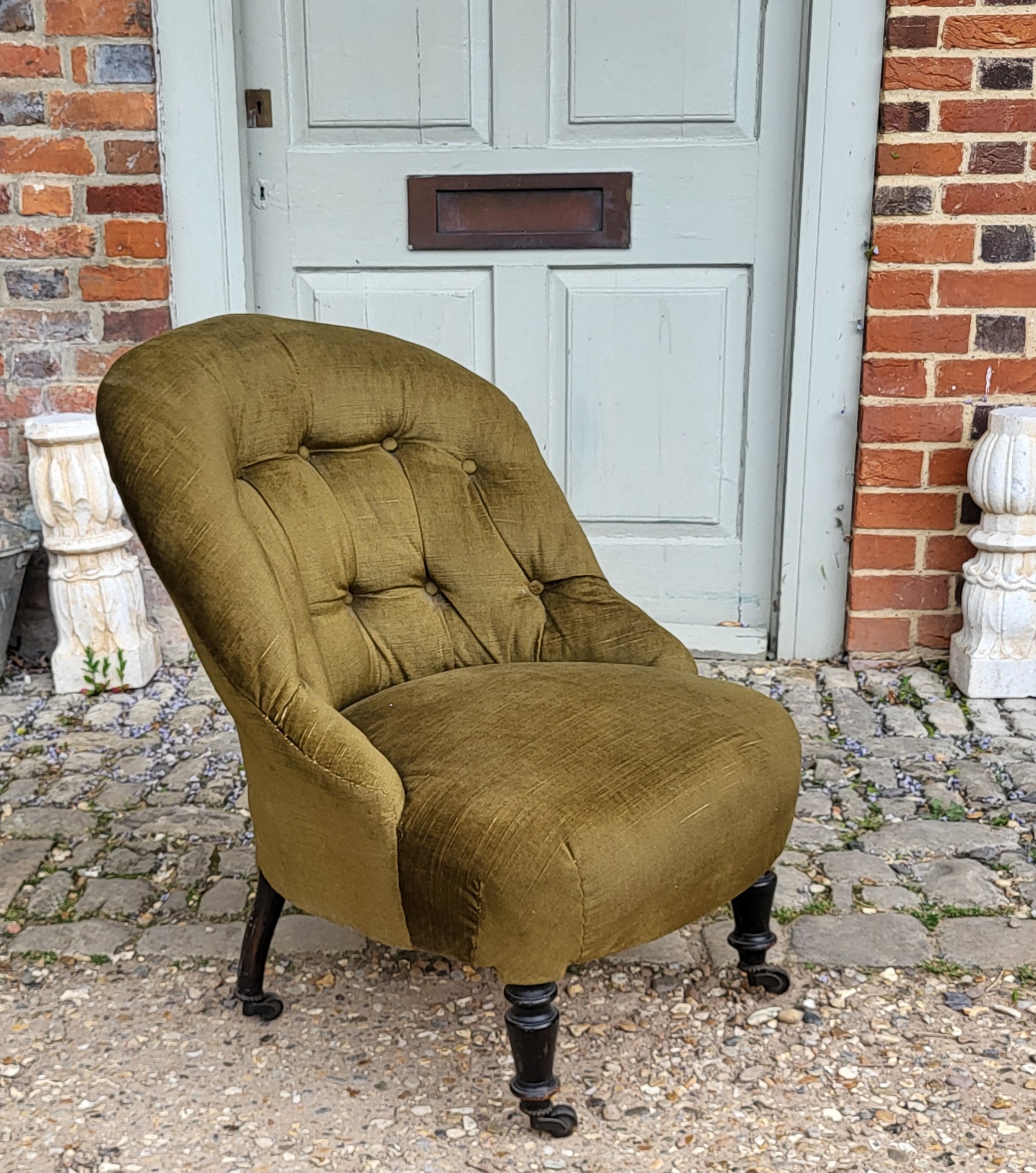 A VICTORIAN NURSING CHAIR Having button back upholstery on turned supports with brass castors. (60cm - Image 2 of 3