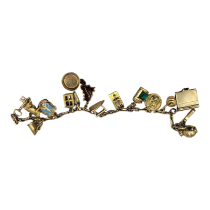 AN EARLY 20TH CENTURY 9CT GOLD CHARM BRACELET Set with thirteen charms including a cow, ship's