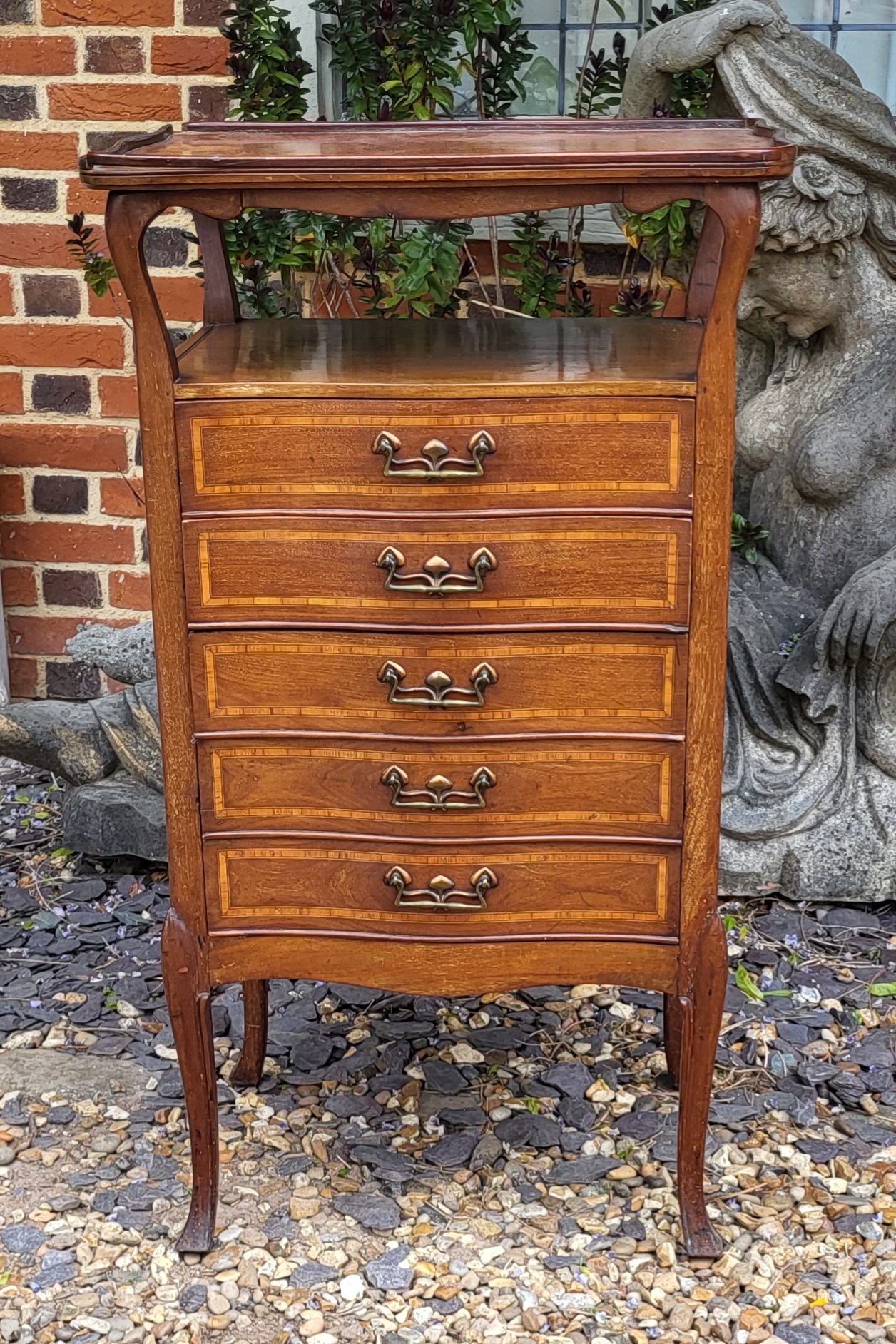 AN ART NOUVEAU MAHOGANY MUSIC CABINET An elevated cartouche shape tray-top above five serpentine