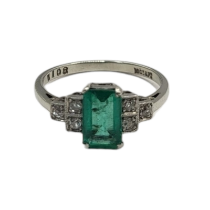 AN ART DECO 18CT WHITE GOLD, DIAMOND AND EMERALD RING The central baguette cut emerald, with round