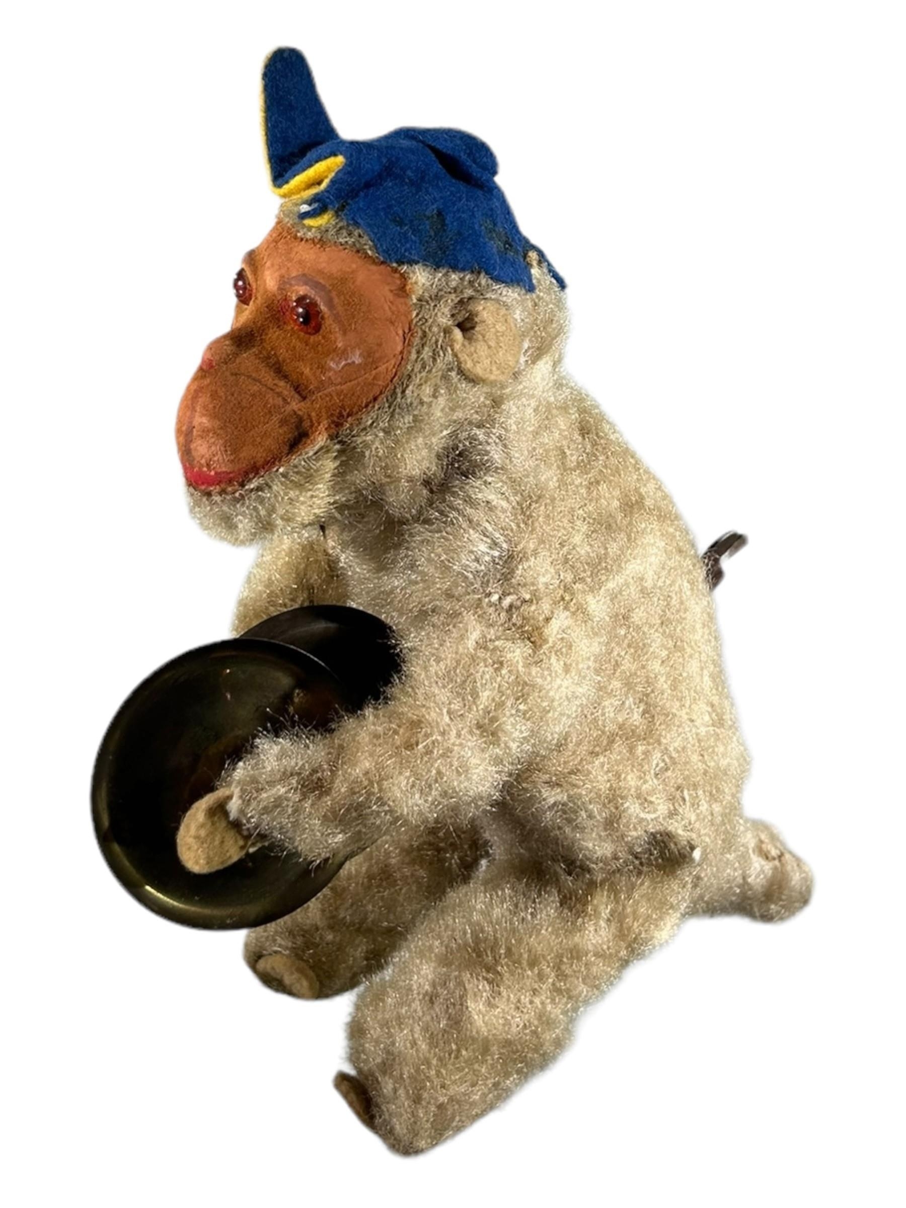 AN EARLY 20TH CENTURY MECHANICAL TOY MONKEY HOLDING SYMBOLS. (h 18cm)