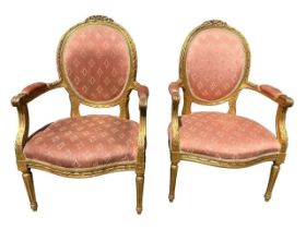 A PAIR OF FRENCH LOUIS XVI DESIGN CARVED GILTWOOD OPEN ARMCHAIRS The oval back with ribbon