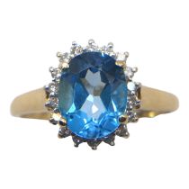A 9CT GOLD, BLUE TOPAZ AND DIAMOND RING Set with a central oval cut blue topaz (approx. 10mm x