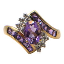 A 9CT GOLD, AMETHYST AND DIAMOND CROSSOVER RING Having central oval cut amethyst (approx. 8mm x