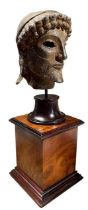 AFTER THE ANTIQUE, A DECORATIVE BRONZED PLASTER HEAD OF ZEUS Raised on a walnut plinth base. (h