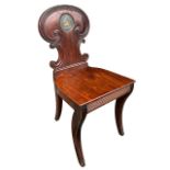 A 19TH CENTURY REGENCY CARVED MAHOGANY HALL CHAIR The shaped back with central painted armorial