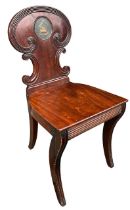 A 19TH CENTURY REGENCY CARVED MAHOGANY HALL CHAIR The shaped back with central painted armorial