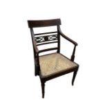 A REGENCY PERIOD MAHOGANY OPEN ARMCHAIR With carved and pierced back rail, cane seat, raised on ring