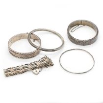 A group of silver bangles and a silver gate bracelet,