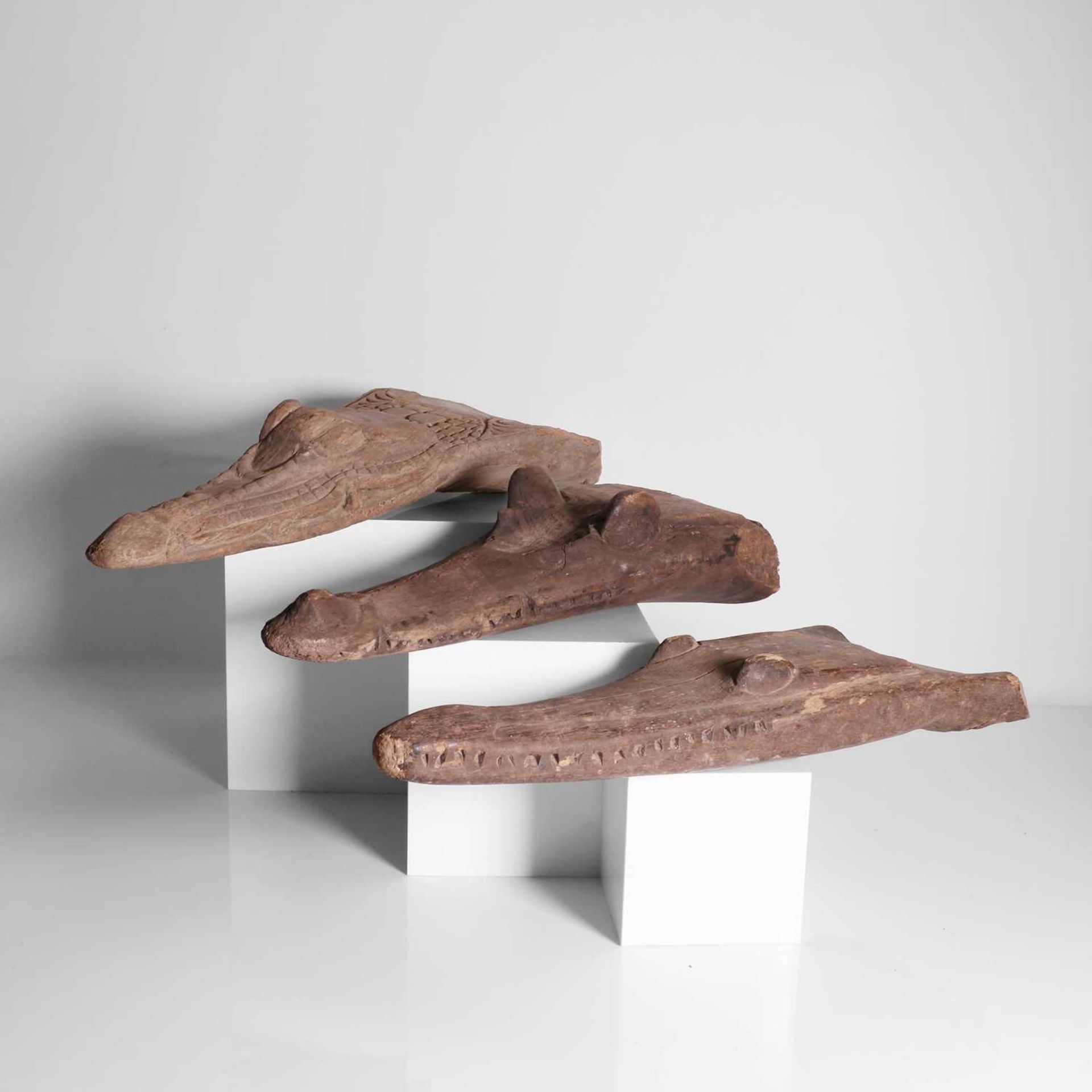 A group of three carved crocodile boat prows,