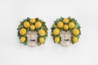 A pair of glazed pottery wall-hanging masks,