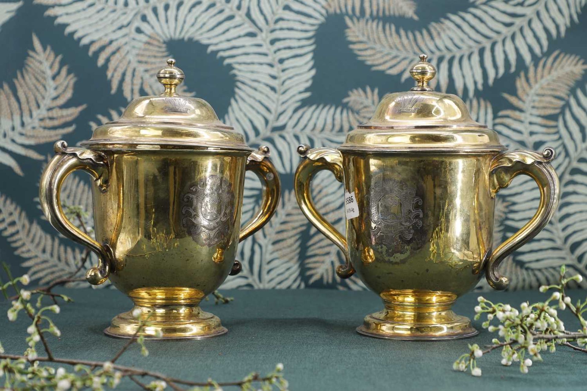 A George I and later composed pair of silver-gilt cups and covers