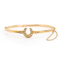 An early 20th century gold split pearl horseshoe bangle,