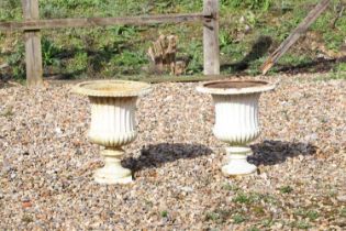 A pair of painted cast iron garden urns,