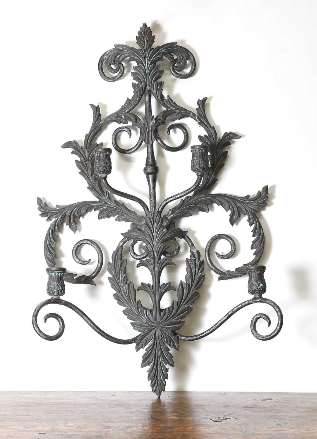 A wrought and cast metal four-arm candle wall sconce,