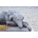 A composition stone figure of a sleeping hound,