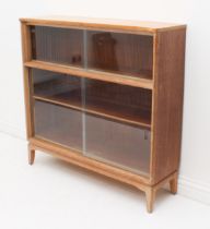 A mid-century light-oak glazed bookcase - the shallow upper section over a lower section with a