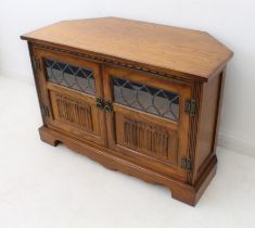 A reproduction carved oak TV / entertainment unit - with a pair of part-glazed doors with